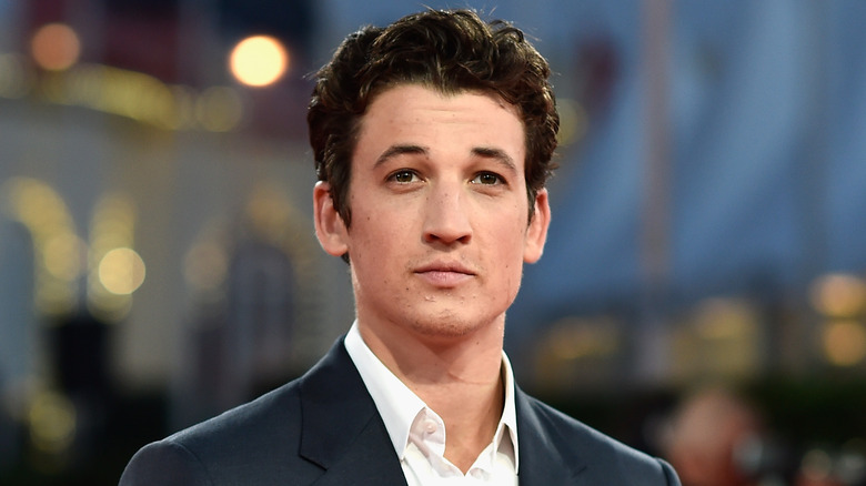 Miles Teller posing in a suit jacket