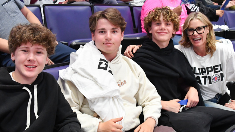 Julie Bowen and sons sitting and smiling at a sports event