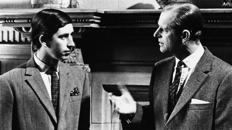 A young Prince Charles and Prince Philip looking at each other sternly