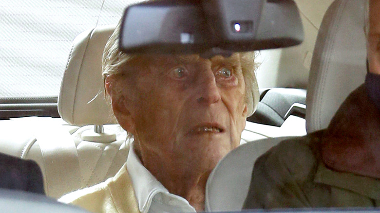 Prince Philip looking grim in the backseat of car
