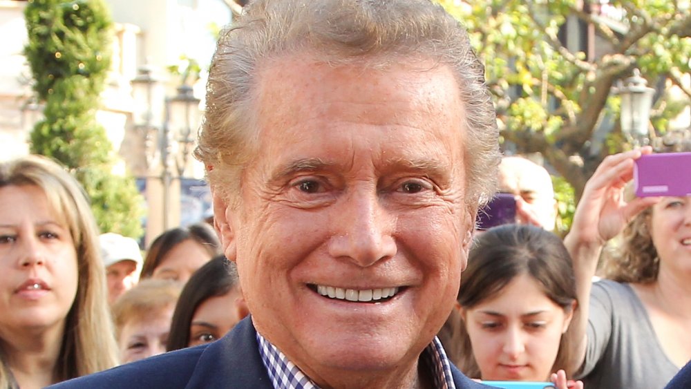 Regis Philbin in a blue blazer and checkered shirt, smiling