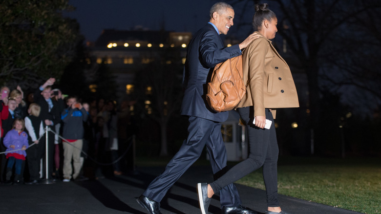 Barack Obama walking with a backpack-clad Sasha Obama at the White House.
