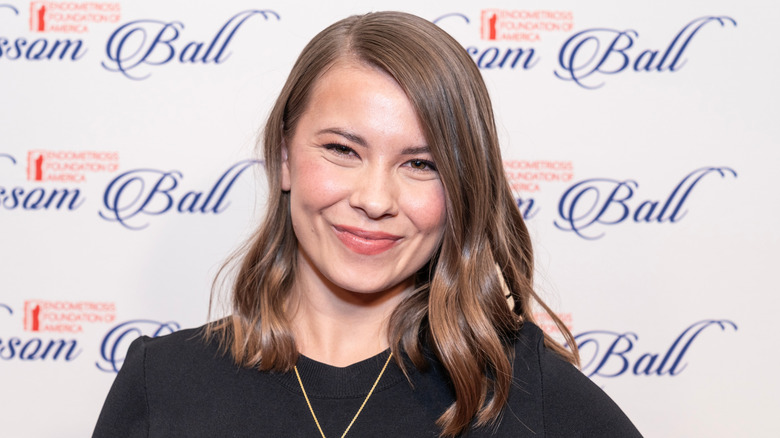 Bindi Irwin wearing a black long sleeved top and gold necklace