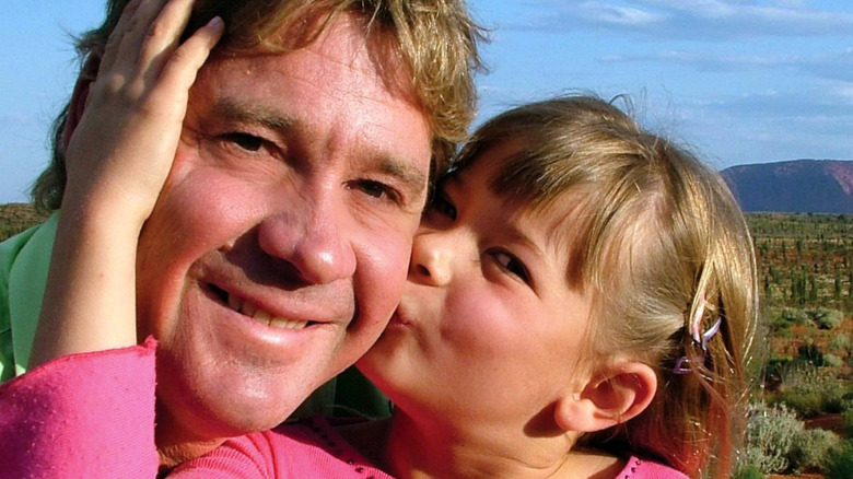 Steve Irwin and a young Bindi Irwin wearing a pink shirt and kissing her dad's cheek