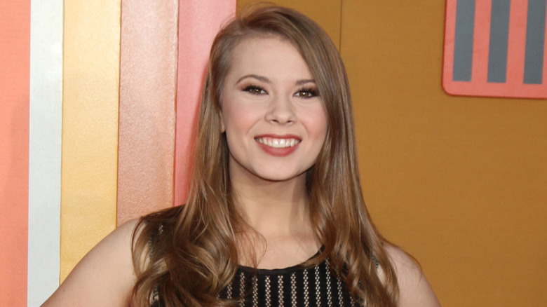 Bindi Irwin with long hair wearing a black lace sleeveless dress