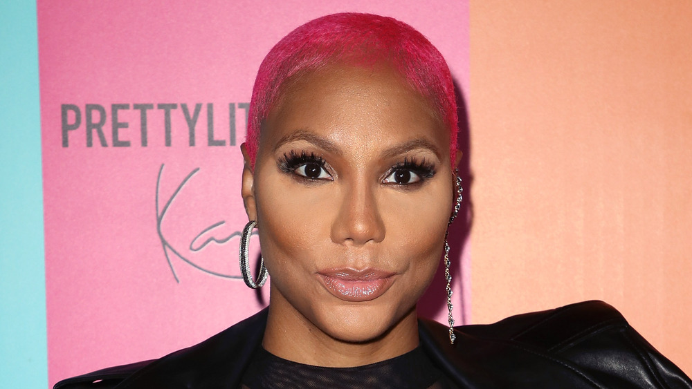 Tamar Braxton with pink hair looking at camera