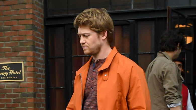 Joe Alwyn looking sad while walking in orange jacket