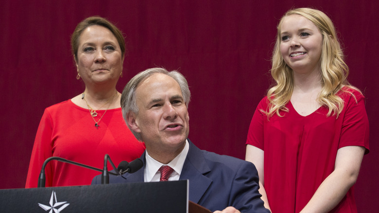 Greg Abbott speaks with Cecilia and Audrey Abbott standing behind him