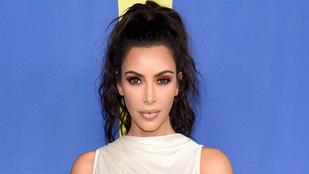 Kim Kardashian posing with a neutral expression in a white dress