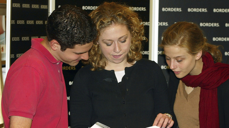 Chelsea Clinton reading a book as two others look in