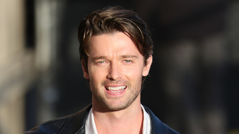 Patrick Schwarzenegger with tousled hair smiling outside