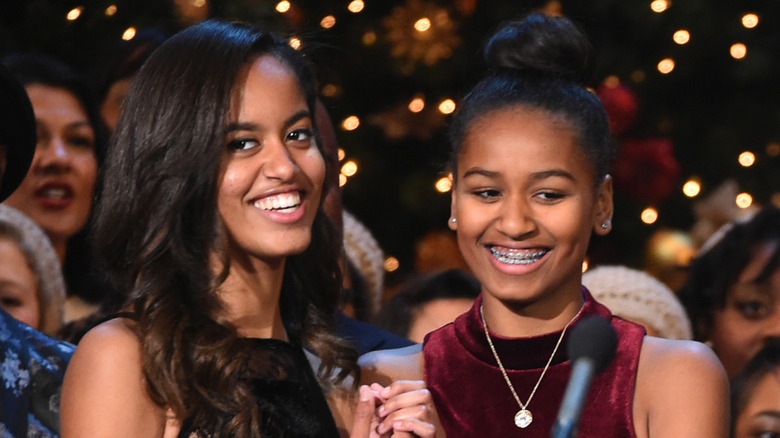 Malia and Sasha Obama looking ahead while standing on stage