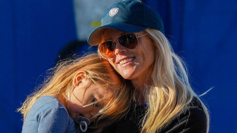 Elin Nordegren smiling while holding her child