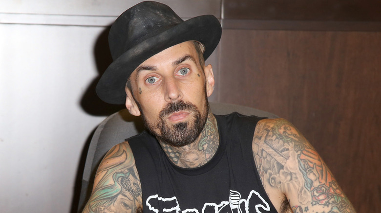 Travis Barker wearing black hat and vest