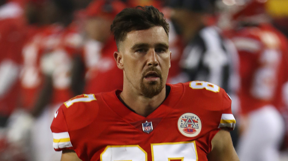 Travis Kelce, serious face, in uniform, on the field, longer hair, goatee