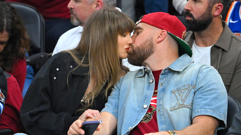 Taylor Swift and Travis Kelce kiss courtside.