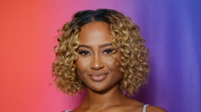 Kayla Nicole smiling while posing in front of a multicolored background