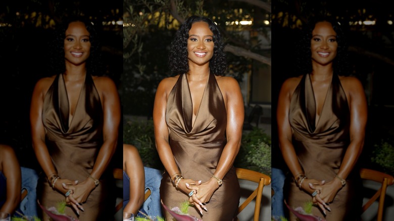Kayla Nicole smiling while posing in a brown silk dress