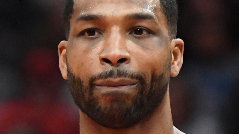 Tristan Thompson smiles in front of orange background