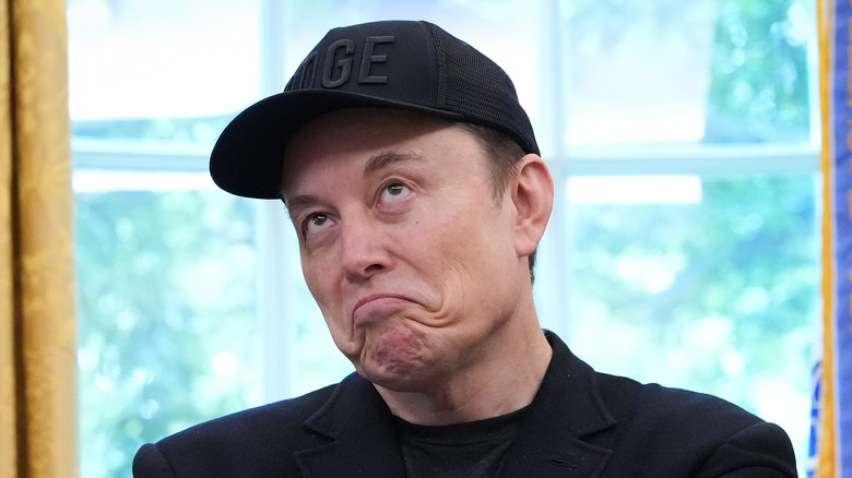 Elon Musk wearing a DOGE baseball cap and making a face