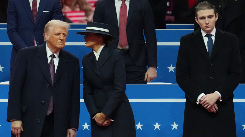 Melania Trump whispers to Donald Trump, while Barron Trump stands nearby