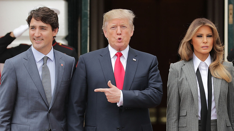 Donald Trump points to Justin Trudeau, while standing next to Melania Trump