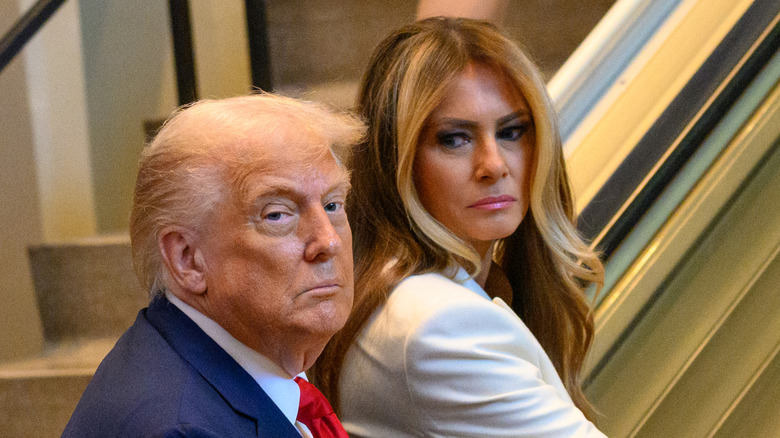 Melania Trump glaring angrily at Donald Trump as they ride an escalator
