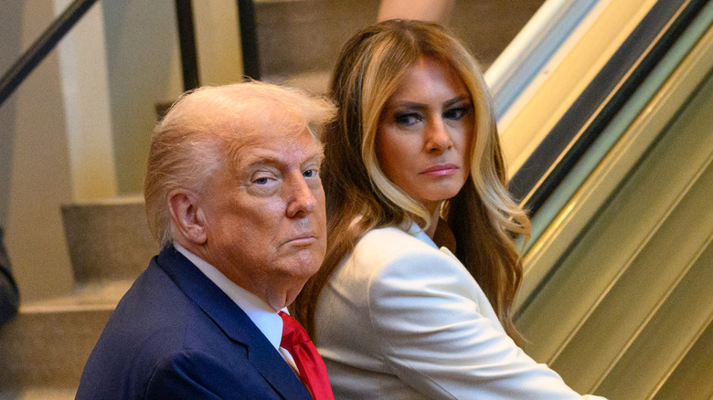 Melania Trump looking at Donald Trump while riding an escalator