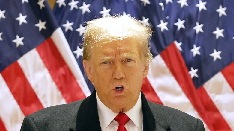 Donald Trump speaking in front of American flags