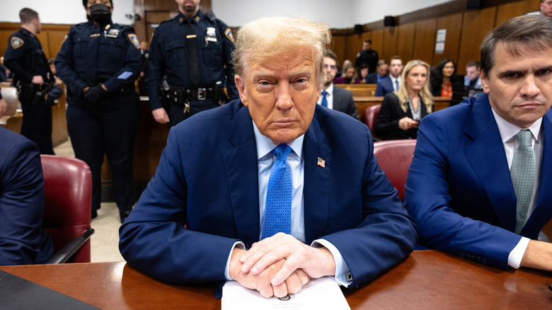 Donald Trump sitting in court with an orange face