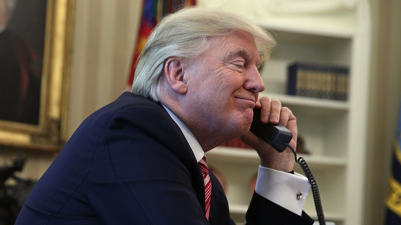 Donald Trump making a phone call in the Oval Office.