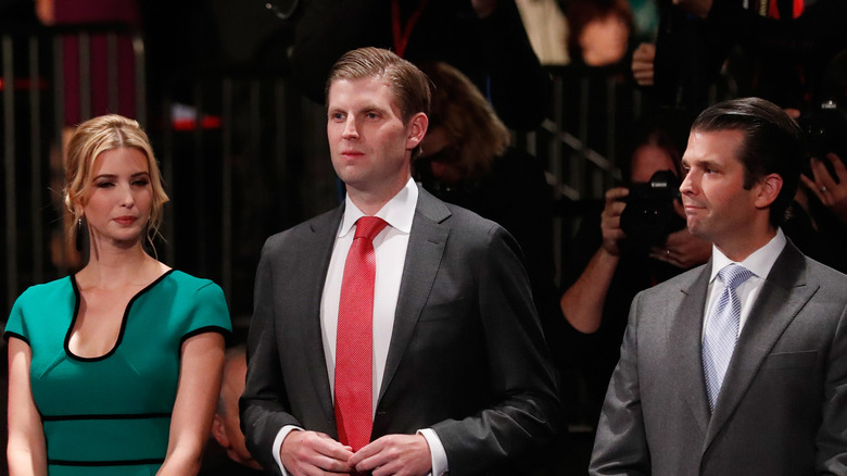 Ivanka Trump wearing a green dress next to Eric Trump and Donald Trump Jr.
