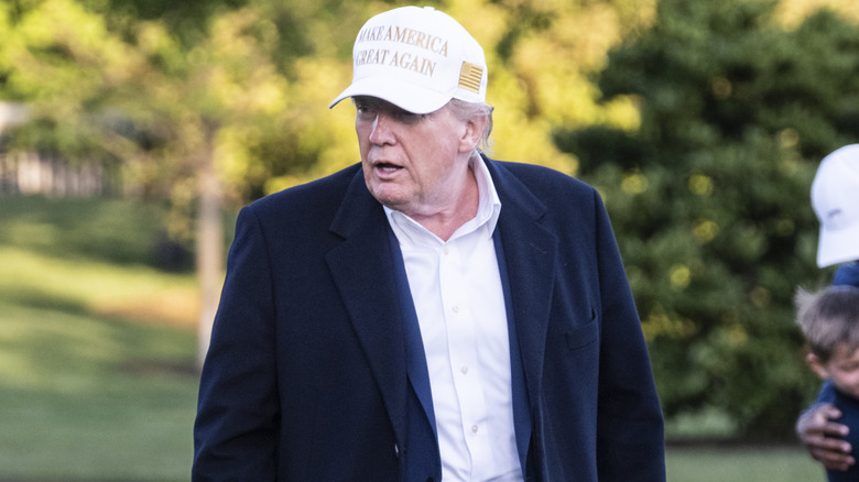 Donald Trump pictured on a golf course in a white MAGA cap.