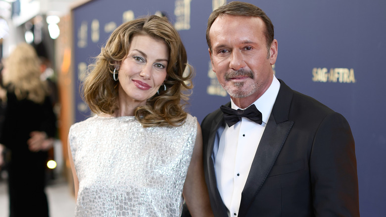 Faith Hill in a boat neck silver sparkling gown with Tim McGraw in a black tuxedo and bow tie
