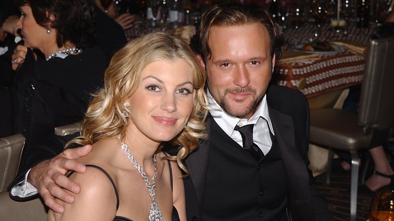 Faith Hill wearing a strappy black dress and large silver necklace with Tim McGraw wearing a black suit and black tie