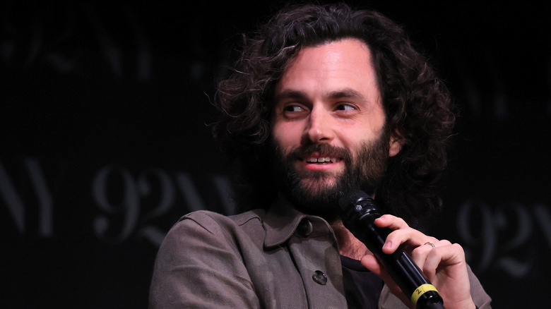 Penn Badgley on stage holding a microphone