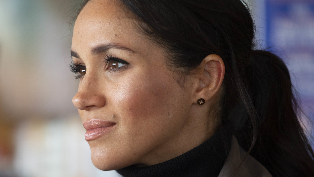 Meghan Markle looking off into the distance wearing a ponytail