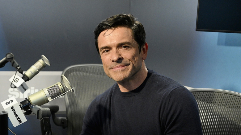 Mark Consuelos smiling next to a microphone at Hits 1 in March 2026.