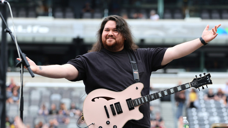 Wolfgang Van Halen raising his arms on stage