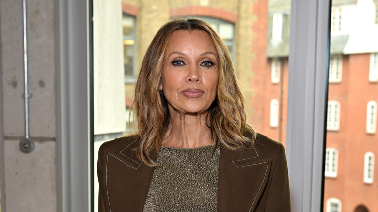 Vanessa Williams posing at an event in a brown suede jacket with a sparkly light brown top underneath