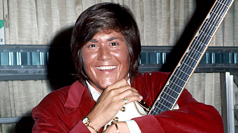 Wayne Newton smiling while posing for a photo with his guitar in the early 1970s