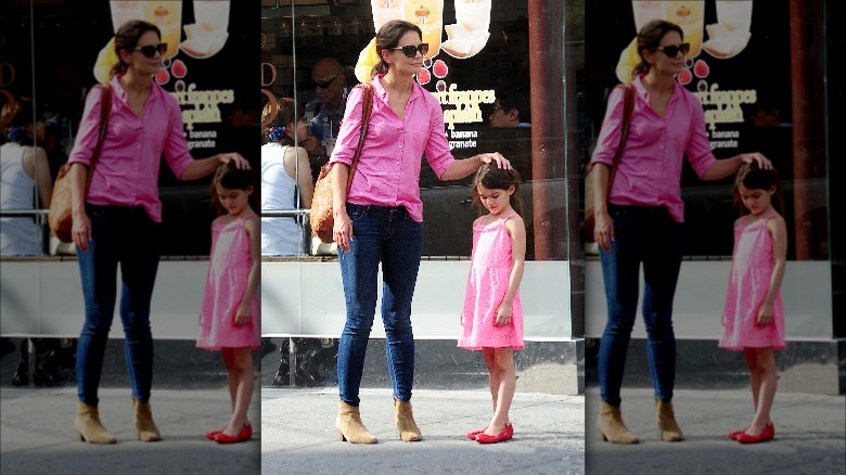 Katie Holmes stands next to Suri