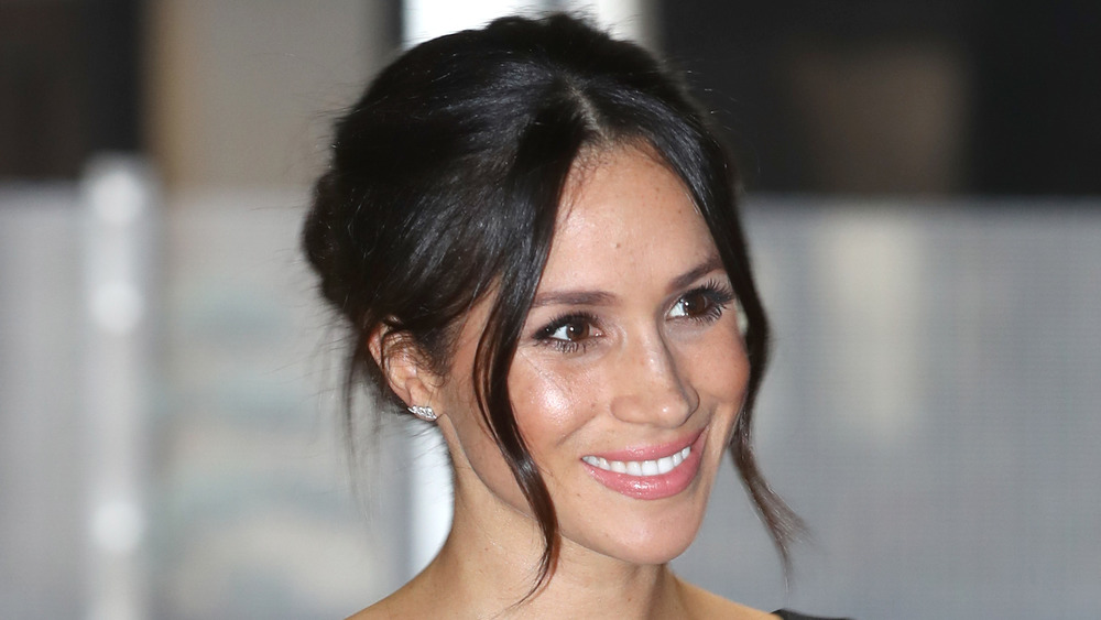 Meghan Markle smiling with her hair pinned up
