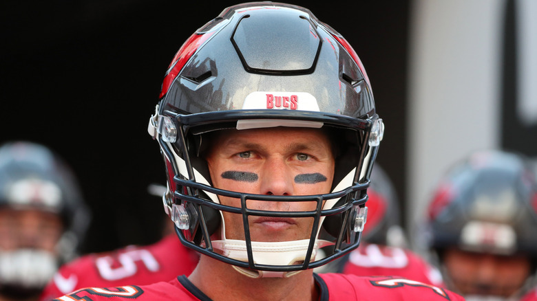 Tom Brady wearing a football helmet while staring at camera