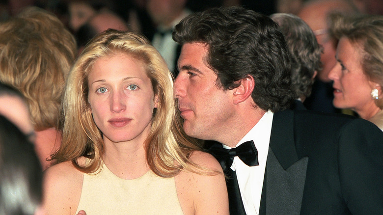 Carolyn Bessette-Kennedy gazes at the lens as John F. Kennedy Jr. whispers in her ear.