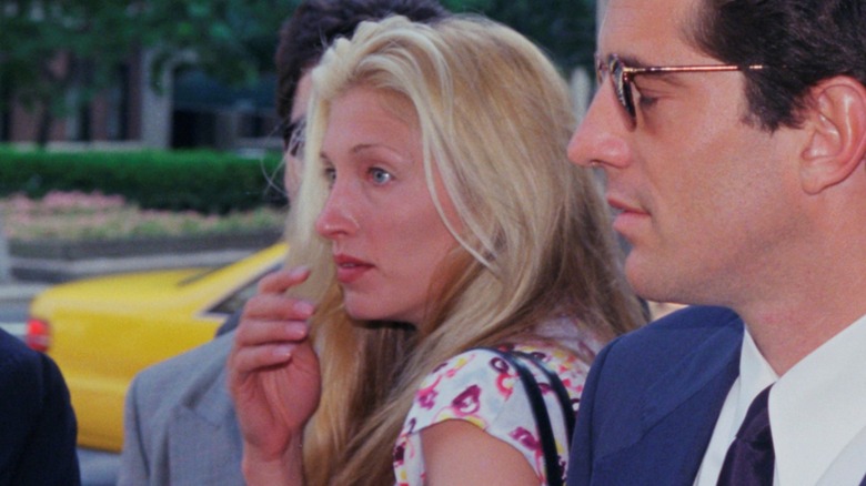 Carolyn Bessette-Kennedy fixes her gaze in the distance, her hand nearly touching her face.