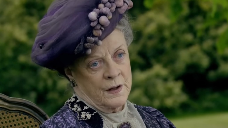 Dressed in a purple headpiece and a matching outfit, Maggie Smith looks away from the camera in her portrayal of Violet Crawley on "Downtown Abbey."