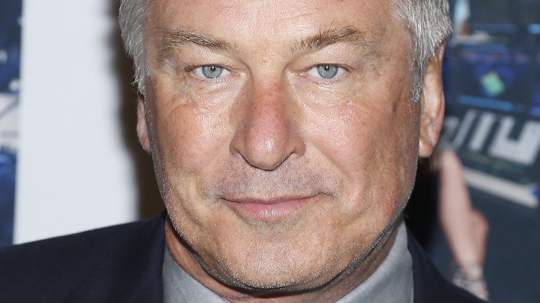 Alec Baldwin posing in a navy suit.