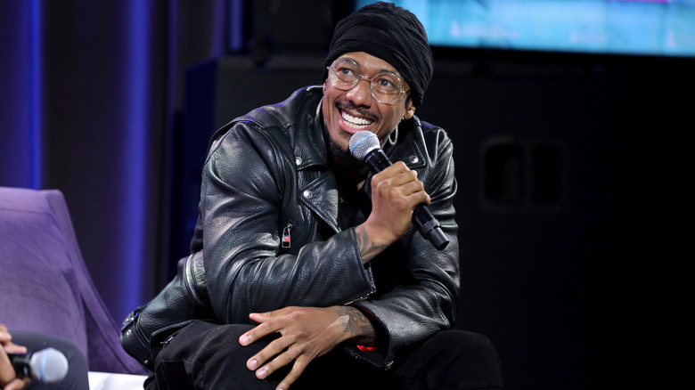 Nick Cannon holding microphone, seated