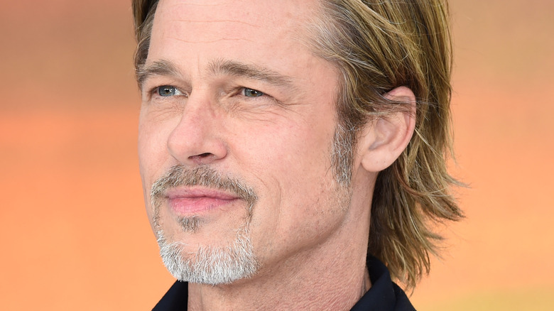 Brad Pitt smirking in front of an orange wall